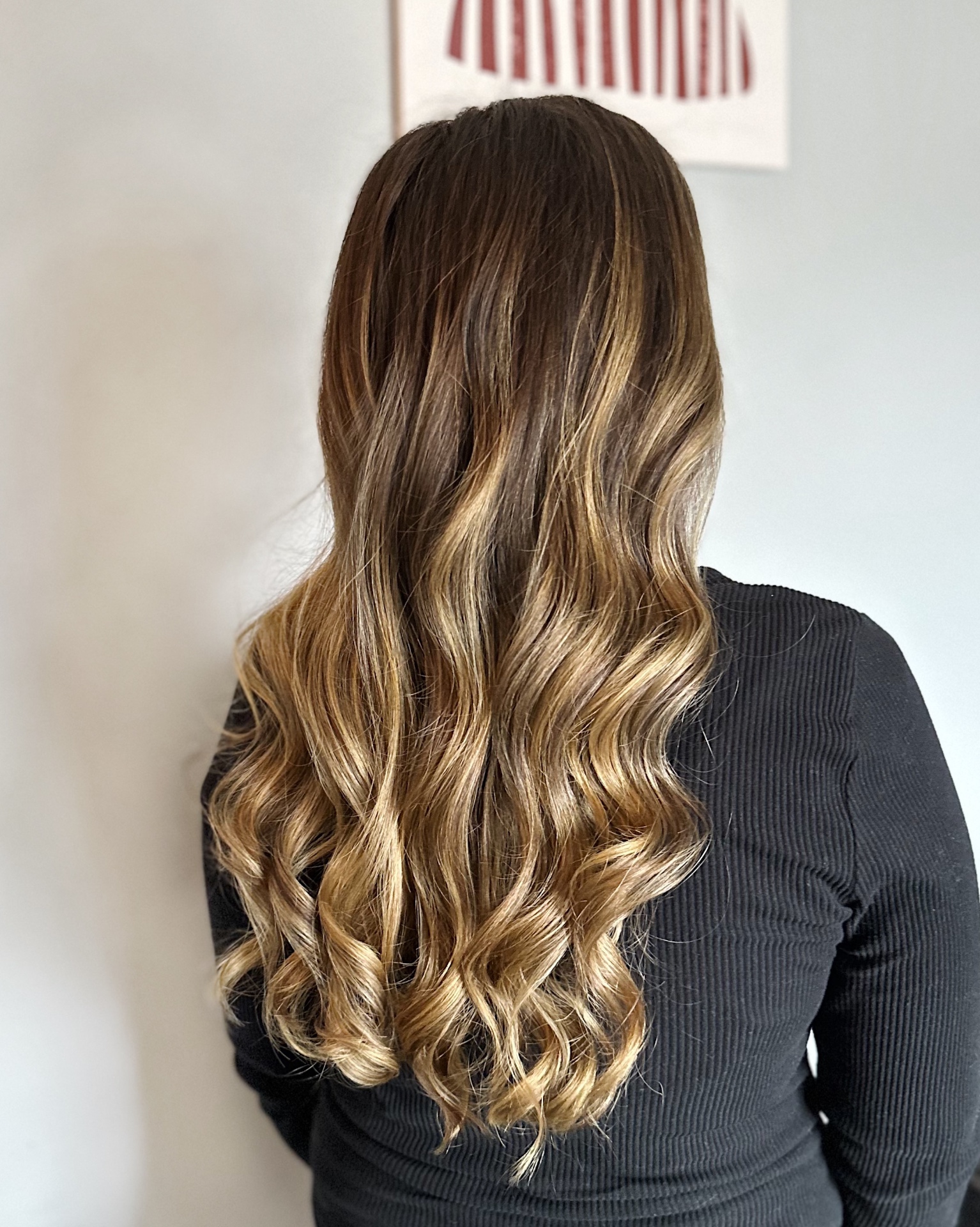 Dimensional brunette balayage with sun-kissed blonde ends styled in soft waves by Jenna Lauren Hair Designs